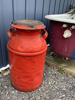 Full view of red milk can beside tub