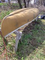 Full side view of overturned yellow canoe on wooden supports