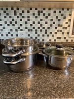 Overall view of stacked stainless pots and separate lidded pot