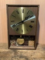 Front view of rectangular wooden wall clock with brass dial and seed inlay panel