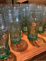 Side view showing multiple green Coca-Cola tumblers with embossed logo