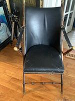 Front view of black leather folding chair showing seat, back and armrests