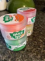 Stack of three Hand Gum putty tubs showing labels and colours
