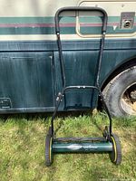 Full view of push reel mower against vehicle