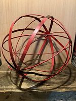 Full view of the red metal orb resting on bench