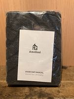 front view of packaged grey door mat with visible AmzGod manual