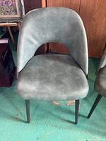 Front view of one green accent chair showing upholstery and leg style