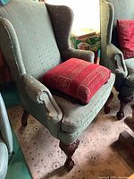 First chair with red pillow, showing fabric pattern and carved legs