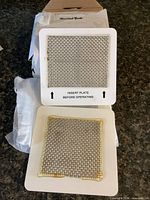 Two Homeland Goods ozone filter plates on countertop, one wrapped box in background