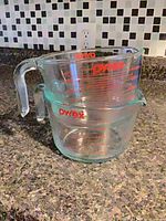 Two stacked Pyrex measuring cups displaying size difference and red graduations