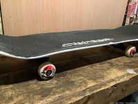 Side view of complete skateboard on workbench showing wheels, trucks, and deck profile