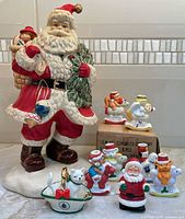 Group shot of all items including large Santa, Spode cat, wind-up Santa, candle holders and Giftco box