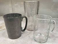 Three measuring vessels: pewter tankard, tall Umpire jar, Pamco cup