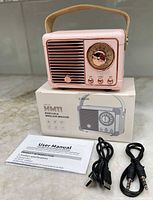 Speaker on top of box with accessories and manual
