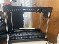 Assembled black and metal under-cabinet storage rack showing slide-out shelf and top rail