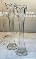 Full view of both clear swung vases showing scalloped rims and entire bodies
