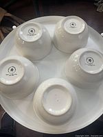 Underside of five white bowls showing base and makers mark