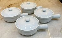Four white ceramic soup crocks with lids