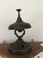 Side view of antique metal service bell showing overall form and patina