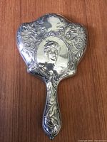 Full view of ornate silver-tone hand mirror back