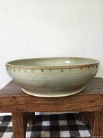 Side view of green glazed stoneware bowl on footed base