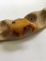 front view of irregular amber brooch on driftwood prop