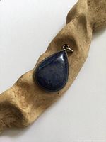 Front view of teardrop lapis lazuli pendant on driftwood