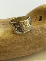 Front view of wide sterling silver band with hummingbird etching