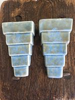 Front view of both ceramic sconces showing stepped design and glaze