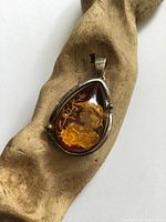 Front view of pendant showing amber cameo and silver setting