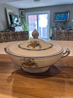 Side view of footed porcelain tureen with lid and handles