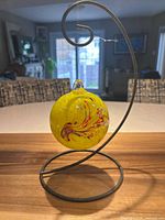 Yellow art glass ball hanging on metal spiral stand