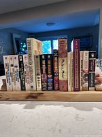 Front view of 17 books standing between wooden bookends