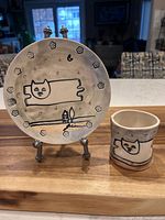 Plate on stand beside matching cup, showing full design