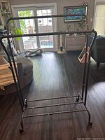 Full view of black metal double-tier garment rack on casters