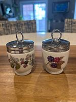 Both Royal Worcester egg coddlers showing fruit motifs and chrome lids