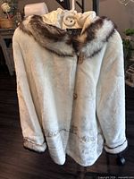 Full view of ivory faux fur hooded jacket on hanger