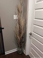 Full view of vase with dried plant arrangement beside door