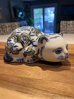 Full side view of ceramic cat figurine displaying blue and green floral pattern