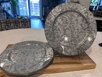 Stack of galvanized metal charger plates on wooden board