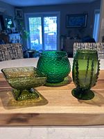 All three green glass items grouped on wood surface