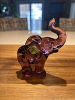 Front view of purple glass elephant figurine showing handpainted leaf motif