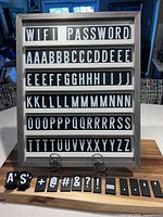 Front view of gray frame message board displaying letter tiles