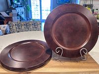 Stack of brown metal charger plates, side angle shows quantity