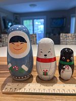 Front view of three painted wooden nesting dolls with ruler for scale