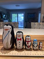 Front view of five nesting dolls lined up with ruler