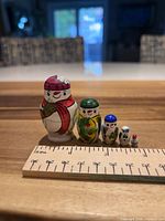 Front view of all five snowman dolls with ruler for scale