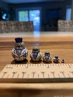 Front view of all five walrus sailor nesting dolls lined up with ruler for scale