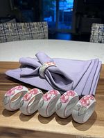 Stack of six lilac napkins with one fitted into porcelain floral ring; five additional rings lined in front