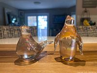Front view of both glass figurines on wood surface